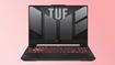 A black ASUS gaming laptop with TUF branding in gray on the screen and red backlit keys to match the gradient background.